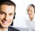 Man with headset smiling while listening to on-hold music and messages